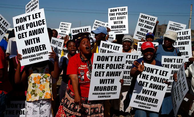 Protesters wave placards as Marikana investigation gets underway