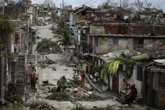People walk on a street littered with debris after Hurricane Sandy hit Santiago de Cuba