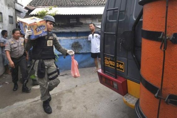 A Special Detachment 88 trooper collects belongings from the house of a suspected militant after a raid in Jakarta