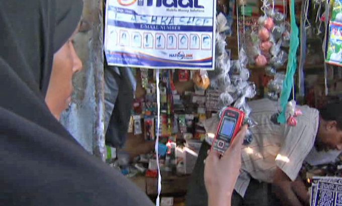 Somali woman using mobile phone - still from Peter Greste package on "e-cash"