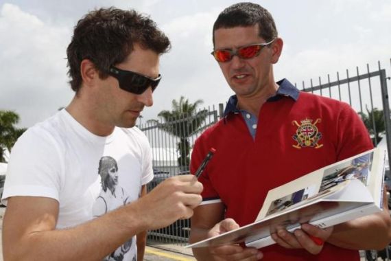Marussia F1 driver Glock of Germany signs an autograph as he arrives at the paddock ahead of the Malaysian Grand Prix in Sepang
