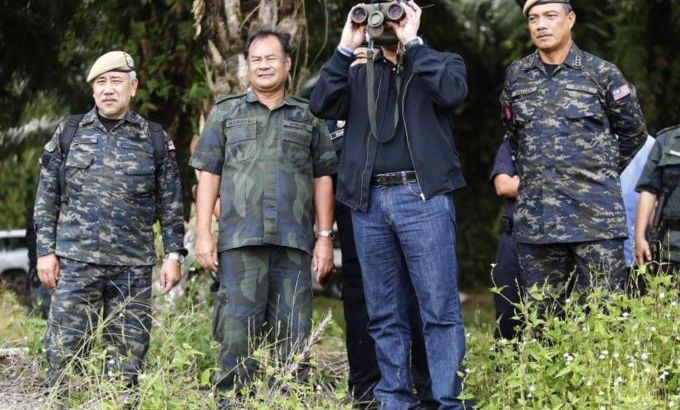 Malaysia''s Home Minister Hishammuddin Hussein looks through binoculars as he visits the area near the location where armed men are holding off, in Sahabat 17 plantation farm, outside Lahad Datu on Borneo island