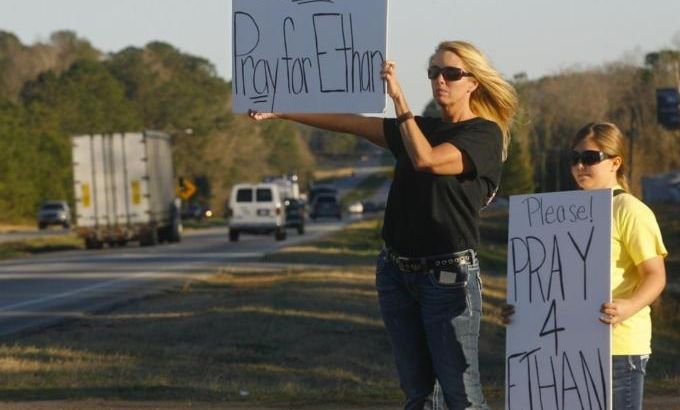 Sherry Johnson Parker and her daughter Olivia Parker, from New Hope, hold signs along Highway 231 asking drivers to pray for Ethan, a 5-year-old boy taken hostage five days ago, after a bus driver was shot and killed near Midland City
