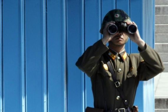 A North Korean soldier looks south through a pair of binoculars on the North side at the