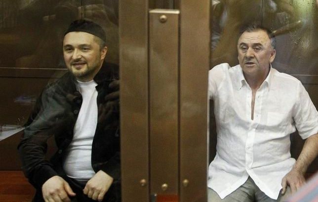 Gaitukayev and Makhmudov sit inside a glass-walled cage before a court hearing in Moscow