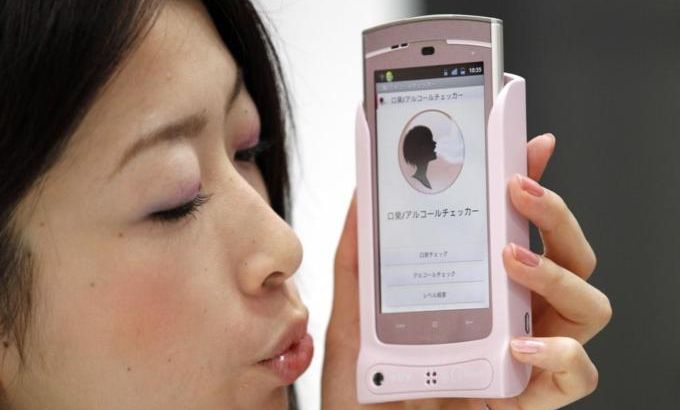 A promotional staff of NTT DoCoMo demonstrates a prototype of smart phone case which measures bad breath at CEATEC JAPAN 2011 electronics show in Chiba