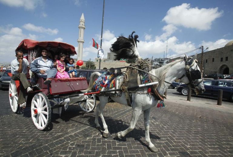 A family rides on a horse-drawn carriage as they celebrate Eid al-Fitr in the port city of Sidon, southern Lebanon