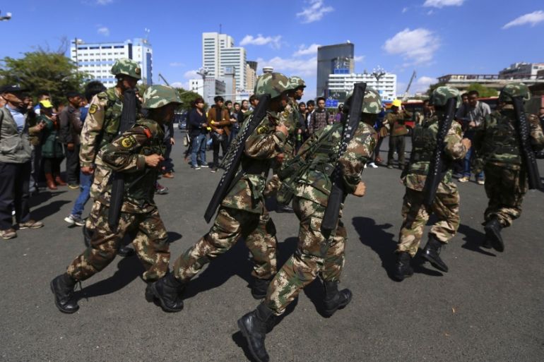 Paramilitary policemen run as they patrol along a street after a knife attack near Kunming railway station in Kunming