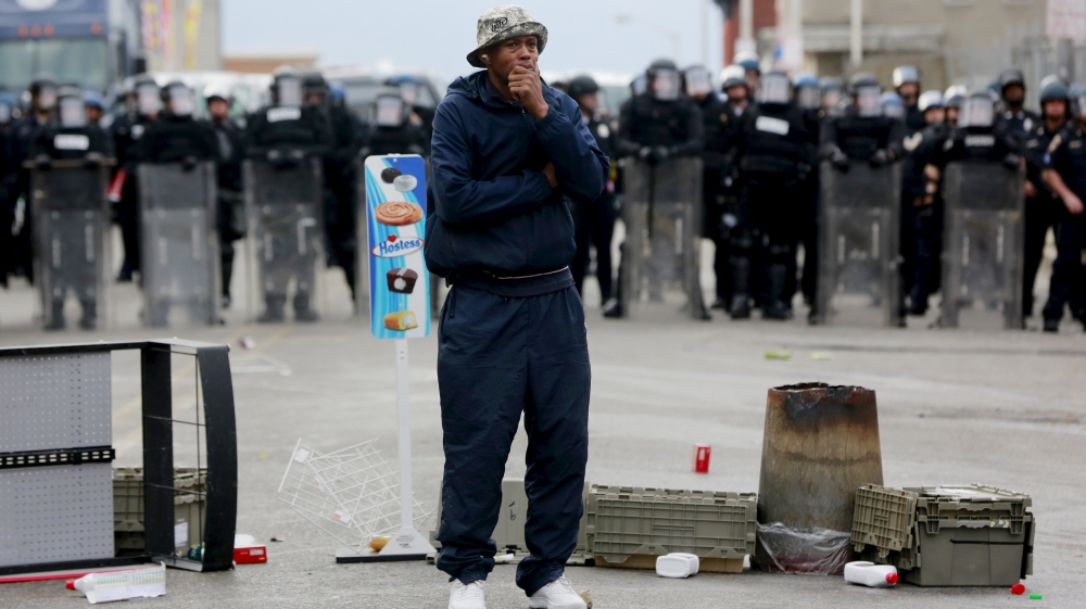 A man stands in front of a police line during clashes in Baltimore [Reuters]