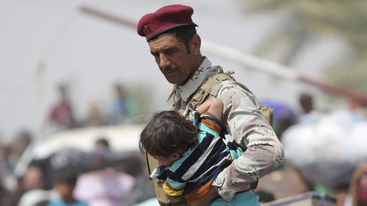 An Iraqi soldier carries a child as displaced Sunni people, who fled the violence in the city of Ramadi, arrive at the outskirts of Baghdad