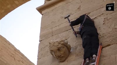 A fighter hammers away at a face on a wall in Hatra, a large fortified city recognised as a UNESCO World Heritage site [AP]