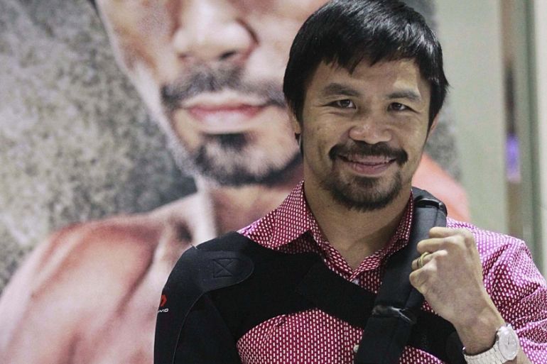 Boxer Manny Pacquiao poses for the members of the media upon his arrival at the international airport in Manila