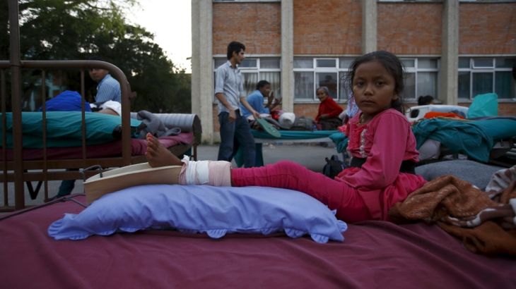A girl lies on a bed after being moved out from the hospital to the open ground for treatment, in Kathmandu
