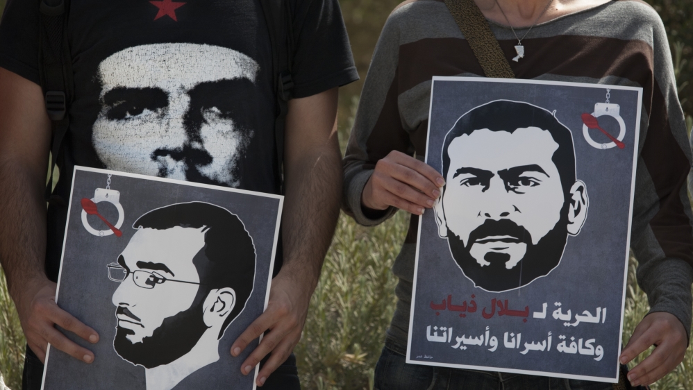 Protesters hold posters depicting the faces of Palestinian prisoners on hunger strike, Thaer Halahleh, left, and Bilal Diab, right  [AP]
