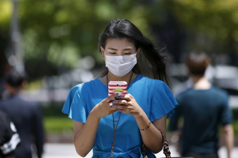 A woman wearing masks to prevent contracting Middle East Respiratory Syndrome (MERS) uses her mobile phone at Myeongdong shopping district in central Seoul