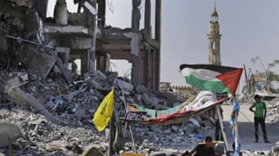 Palestinians stand by the rubble of houses, destroyed by Israeli strikes in northern Gaza Strip [AP]