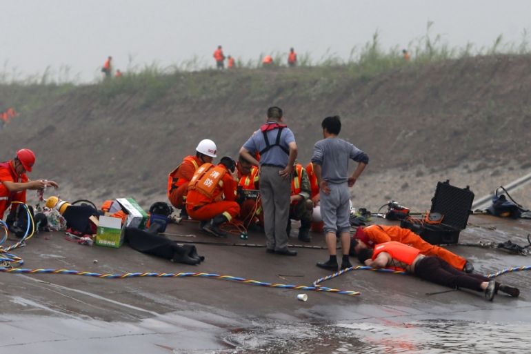 Rescuers listen for reactions from inside a sunken ship as they search for survivors at the Jianli section of the Yangtze River