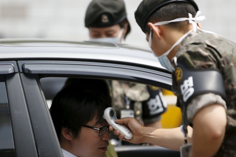 Military officials check the body temperature of visitors at the Defense Ministry in Seoul