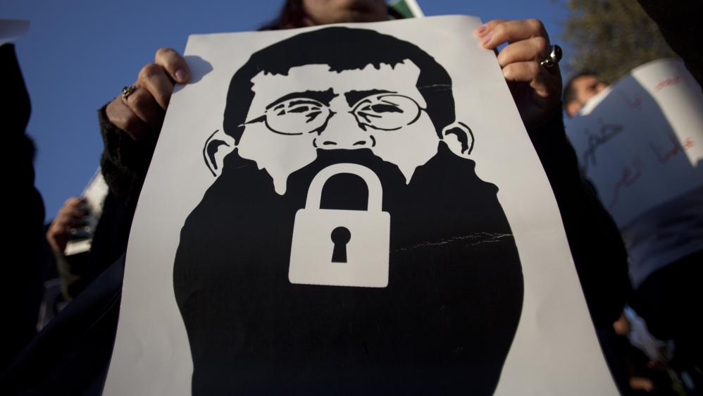 A woman holds up a poster of Palestinian prisoner Khader Adnan in a 2012 demonstration. Adnan had been in prison and on hunger strike for two months [AP]
