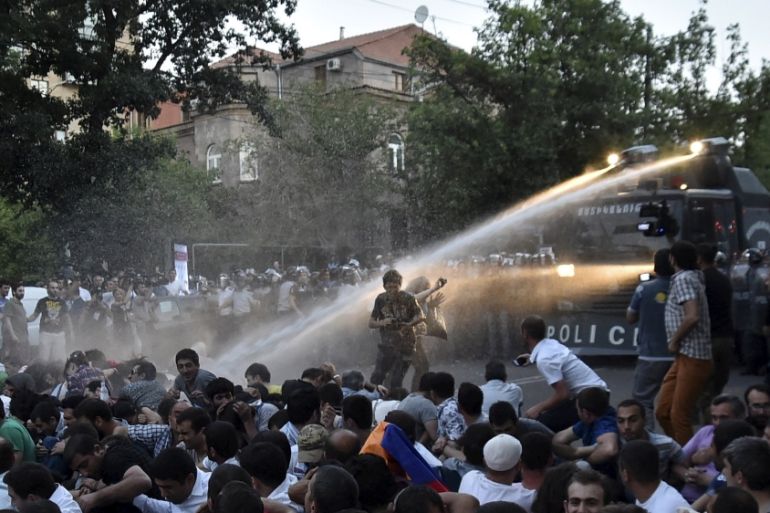 Riot police vehicle sprays jets of water to disperse protesters during rally against recent decision to raise public electricity prices in Yerevan