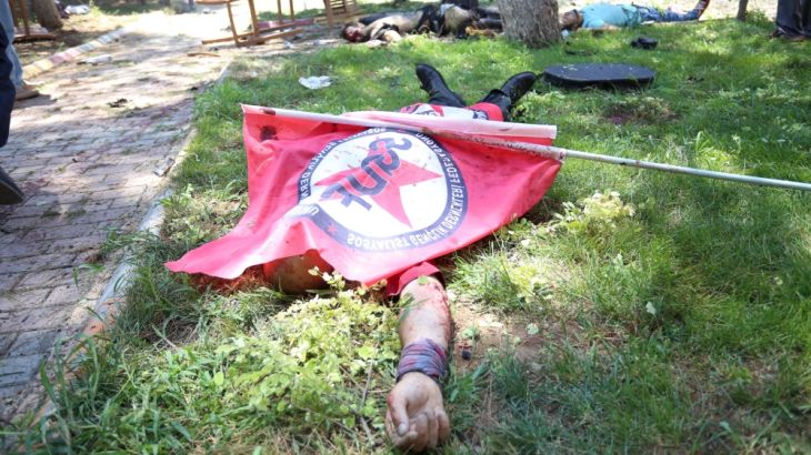A victim, with a flag of the left-wing Federation of Socialist Youth Associations covering him, lies on the ground following an explosion in Suruc