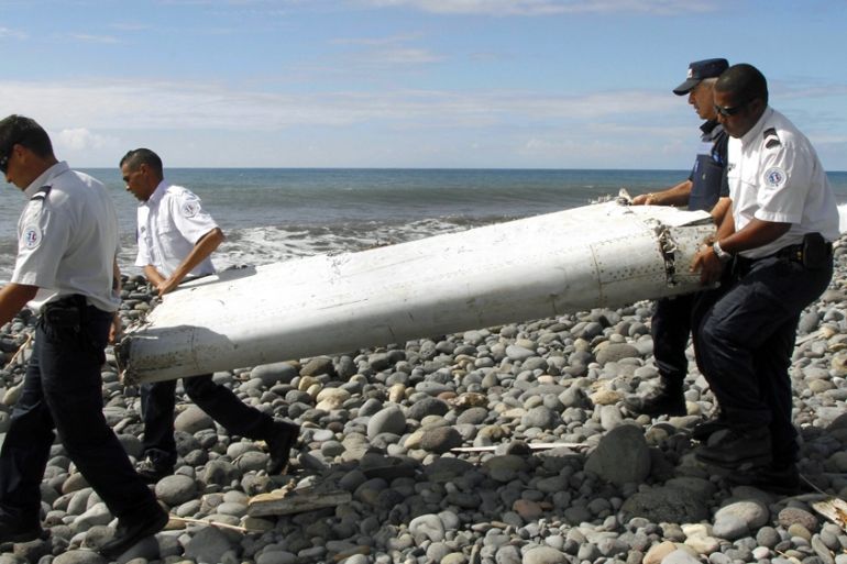 Four men carry a flaperon on the beach on Reunion Island. It was later identified as from MH370
