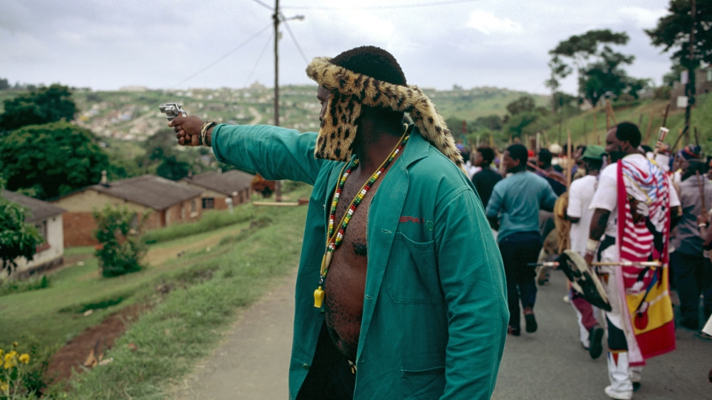 In this photograph taken in 1995 in Durban, an Inkatha Freedom Party supporting chief fires a handgun into houses during a rally in Umlazi Township. When he noticed me taking pictures, he turned on me and I had to beg him not to shoot [Greg Marinovich]