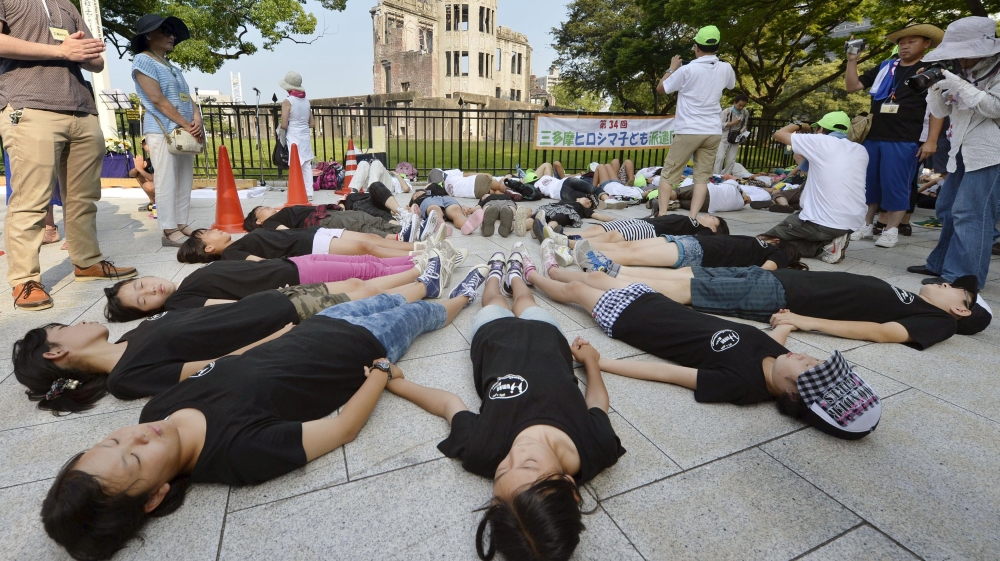  Children perform a die-in in front of the Atomic Bomb Dome at Peace Memorial Park in Hiroshima   [Reuters]