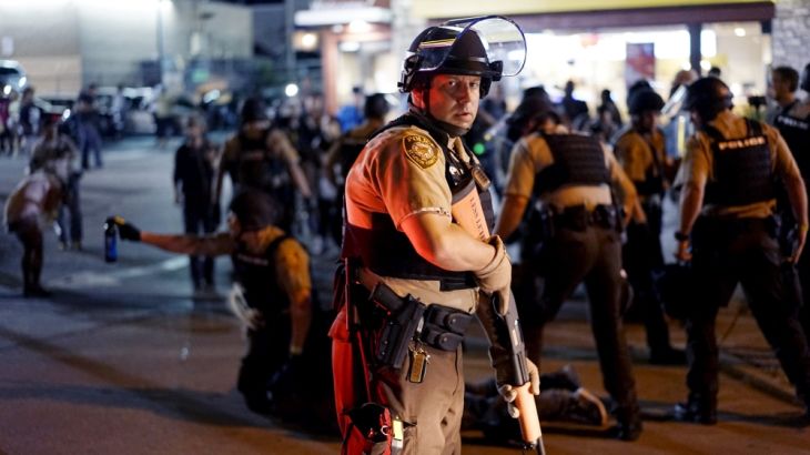 A police officer holds his weapon as a protester is detained in Ferguson