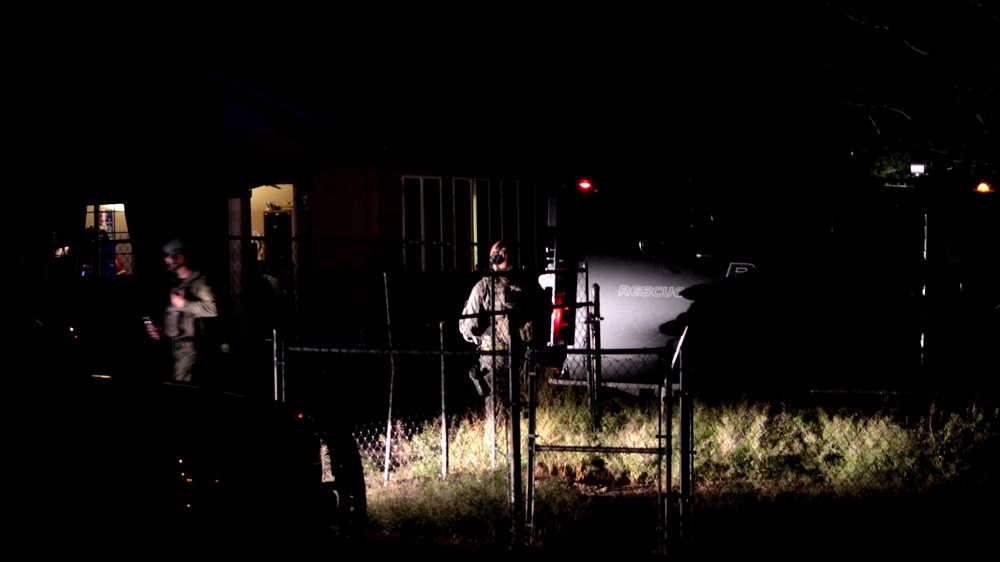Members of the APDs SWAT team enter a house after a suspect surrendered in May 2015. The armoured vehicle used by SWAT is known as a Bearcat, and was frequently seen on the streets of Ferguson, Missouri, during protests following the police killing of 18-year-old Michael Brown last year [Andy Beale/Al Jazeera]