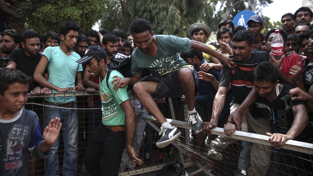 A migrant jumps over a fence as hundreds wait for a registration procedure outside a police station in Kos [AP]