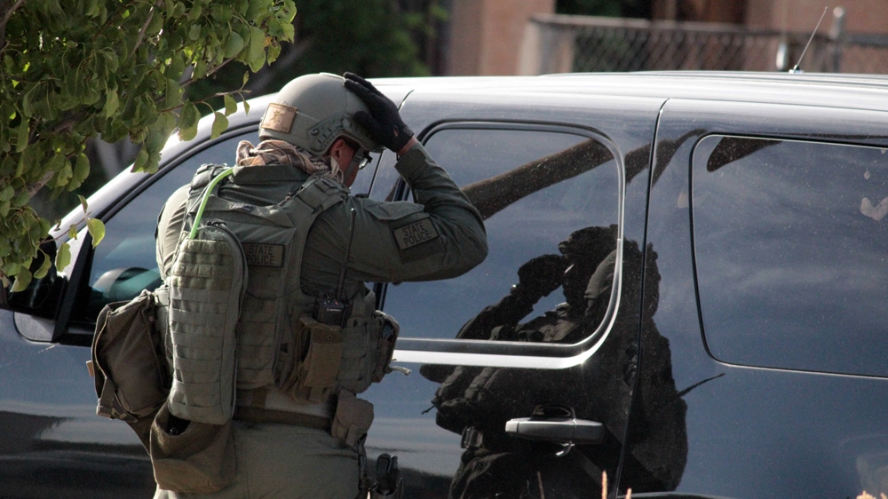 An Albuquerque's SWAT team member uses a police SUV as a mirror to adjust his helmet during a standoff with a mentally ill suspect  in June 2015 [Andy Beale/Al Jazeera]
