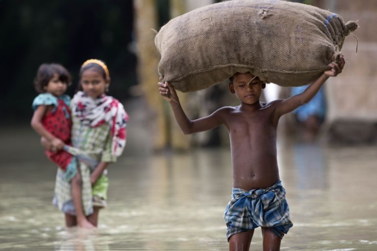 Indian child carries a sack through the floodwaters