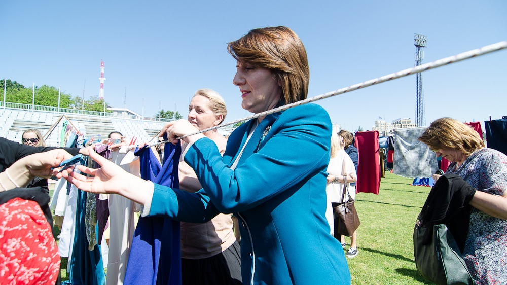 President Jahjaga hangs a dress at Pristina's football stadium in preparation for the unveiling of the art installation called 'Thinking of You,' which she sponsored. Over 5,000 dresses and skirts hung on washing lines as part of the installation [Valerie Plesch/Al Jazeera] 