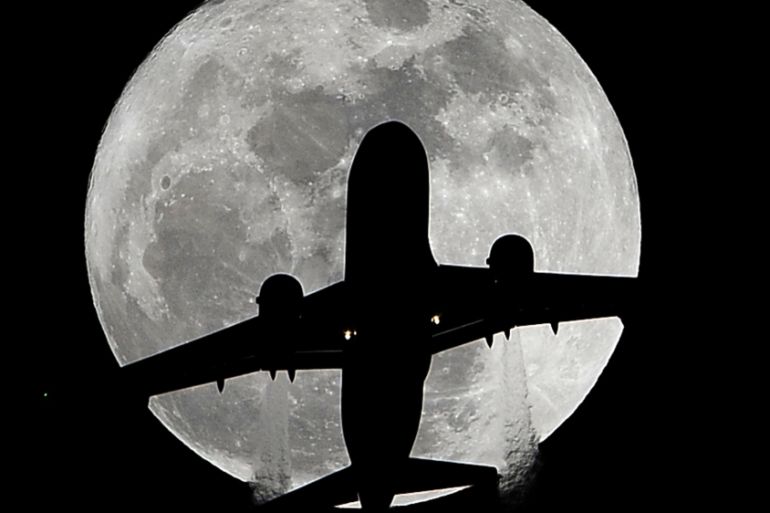 A passenger plane en route to Los Angeles International Airport passes in front of a full moon [AP]
