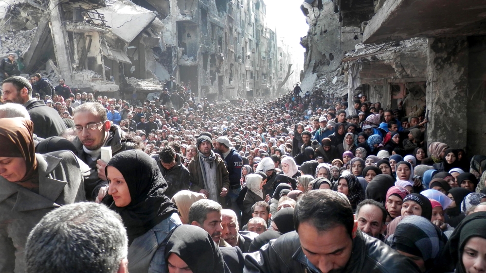 On January 31, 2014, residents of the besieged Palestinian camp of Yarmouk queued to receive food supplies [File: UNRWA/AP] 