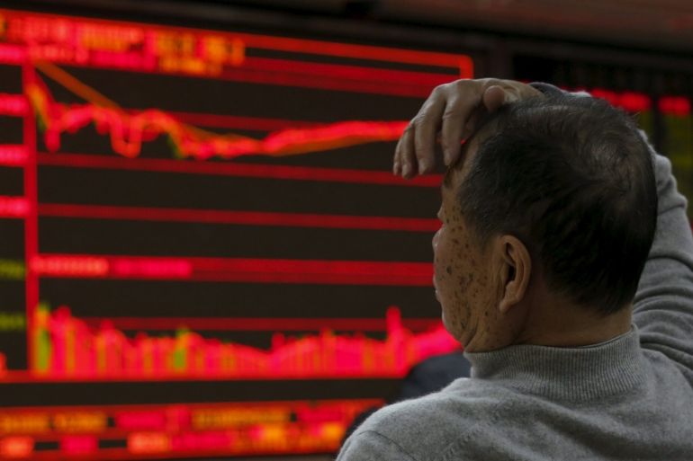 A man looks at an electronic board showing stock information at a brokerage house in Beijing