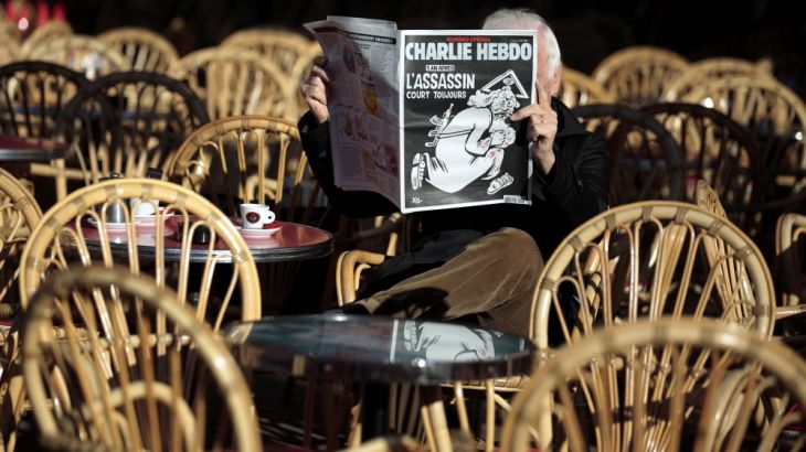 A man reads the latest edition of French weekly newspaper Charlie Hebdo with the title "One year on, The assassin still on the run" on a cafe terrasse in Nice