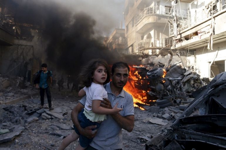 A man carries a girl reacting at a site hit by what activists said were airstrikes by forces loyal to Syria''s President Bashar al-Assad on a market place in the Douma neighborhood of Damascus, Syria