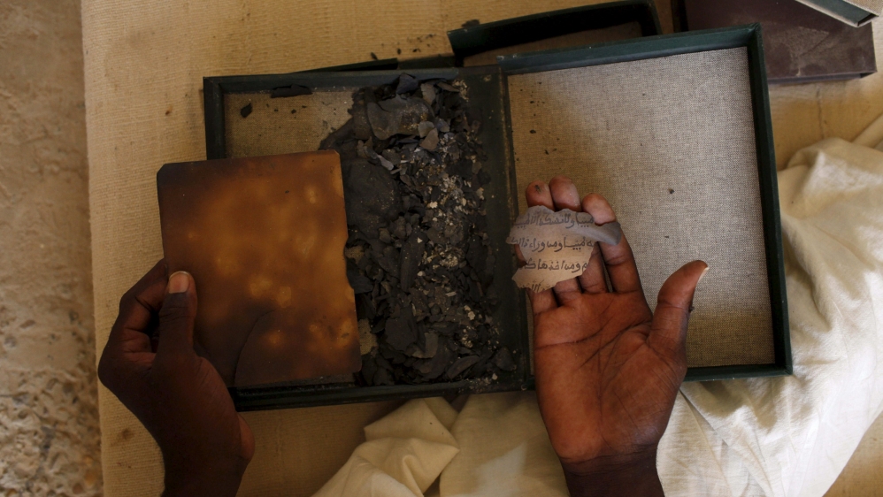 A man holds the remnants of an ancient Islamic manuscript burned by armed groups in Mali [Joe Penney/Reuters]