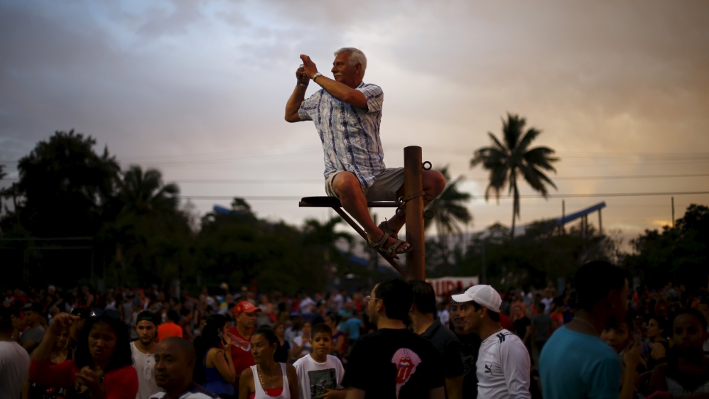 A fan takes a photograph while sitting on a pole before a free outdoor concert by the Rolling Stones [Reuters]