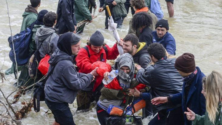 Refugees cross a river near Idomeni to enter Macedonia