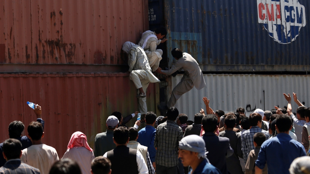 Demonstrators from Hazara minority try to climb up the containers used to block a road during a protest in Kabul [Ahmad Masood/Reuters]