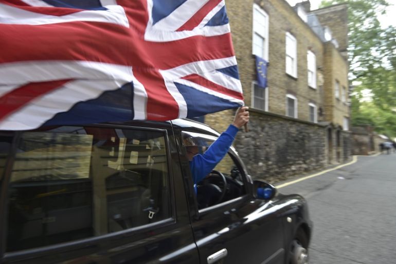 A taxi driver holds a Union flag, as he celebrates following the result of the EU referendum, in central London