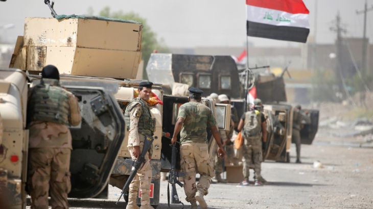 Iraqi army soldiers carry their weapons as they gather in the center of Falluja