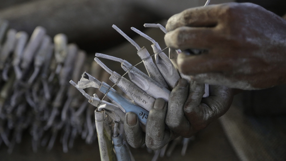 A fireworks factory worker ties the gunpowder-filled paper tubes and wicks with a nylon thread at a factory in Kimbulapitiya [MA Pushpa Kumara/EPA]