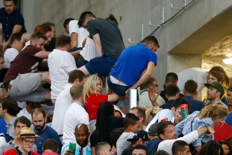 England fans climb over a fence to escape trouble in the stadium after the game