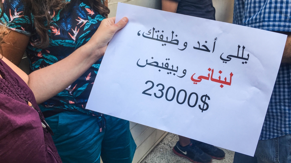 'He who took your job is a Lebanese, and he makes $23,000,' reads a sign at the protest [Sarah Shmaitilly/Al Jazeera]
