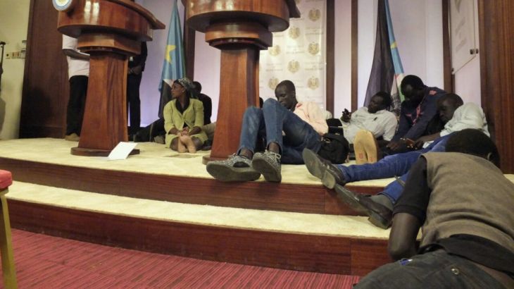 Journalists are seen on the podium following sounds of gun shots before a news conference in Juba