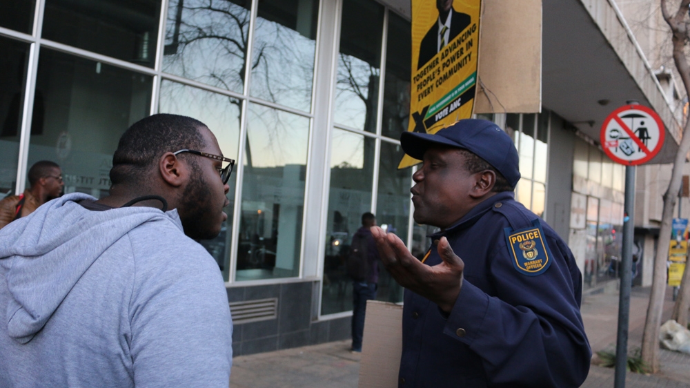 Law student Thapelo Mawasha asks a police officer why he would shoot at young black students and why he doesn't support their struggle [Caelainn Hogan/Al Jazeera]